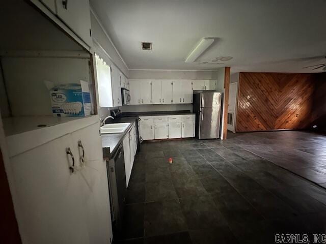 kitchen featuring stainless steel appliances, a sink, white cabinetry, and dark countertops