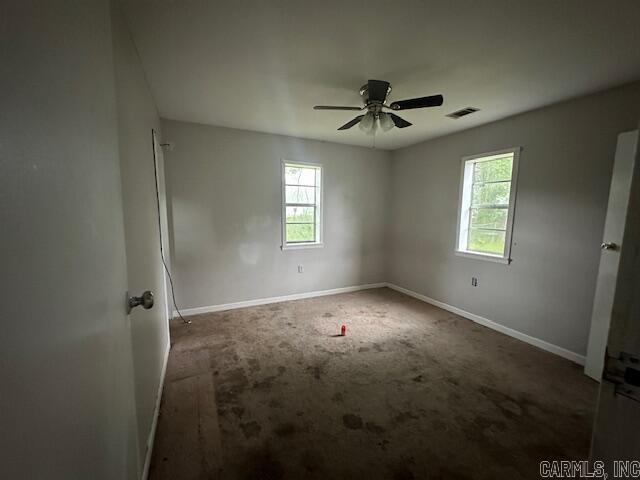 carpeted empty room featuring plenty of natural light, baseboards, and a ceiling fan