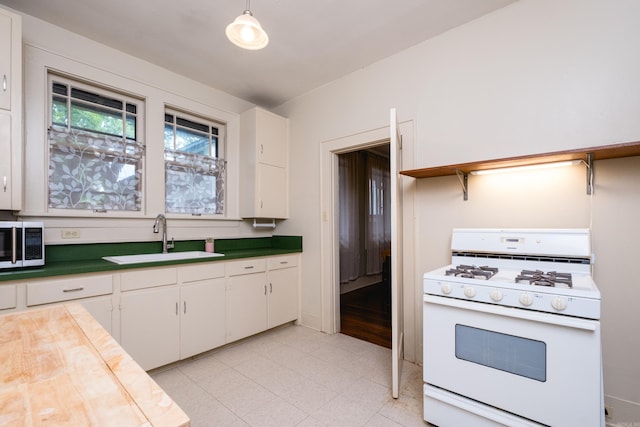 5200 I St, Little Rock, AR 72205 - kitchen with white gas stove, a sink, white cabinets, and hanging light fixtures