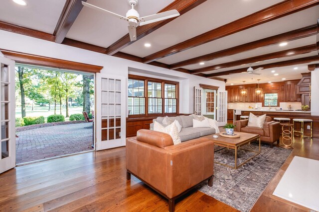 living area with a ceiling fan, beam ceiling, plenty of natural light, wood finished floors, and recessed lighting
