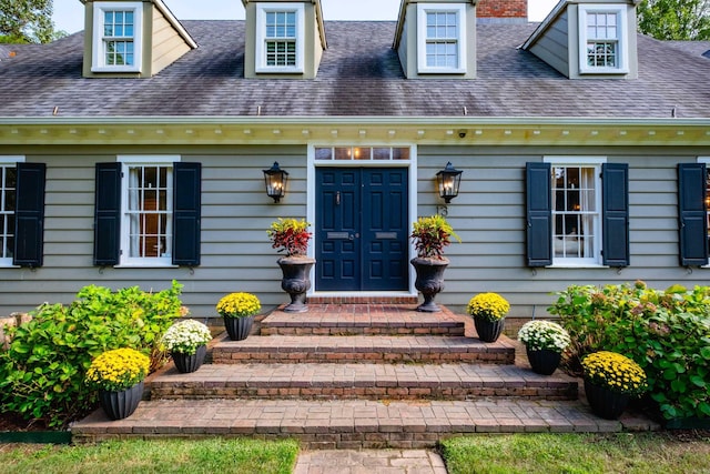 doorway to property featuring a shingled roof and a chimney
