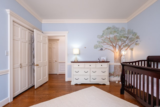bedroom with ornamental molding, wood finished floors, a nursery area, and a closet