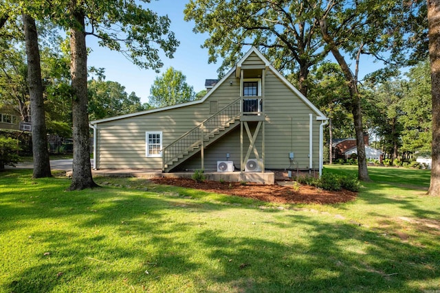 rear view of house featuring a lawn and stairway