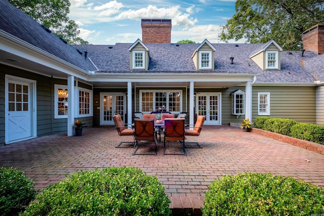 back of property with french doors, a chimney, a patio area, and a shingled roof