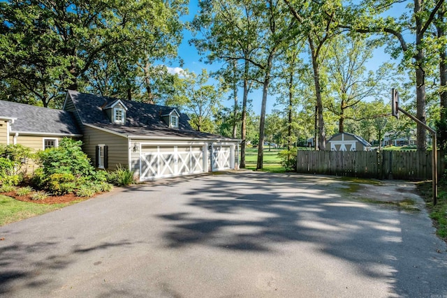garage featuring fence and asphalt driveway