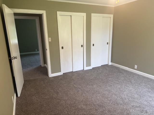 307 E 5th St, Carlisle, AR 72024 - unfurnished bedroom featuring carpet floors, ornamental molding, multiple closets, and baseboards