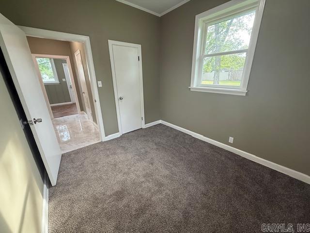 307 E 5th St, Carlisle, AR 72024 - unfurnished bedroom featuring dark colored carpet, ornamental molding, and baseboards