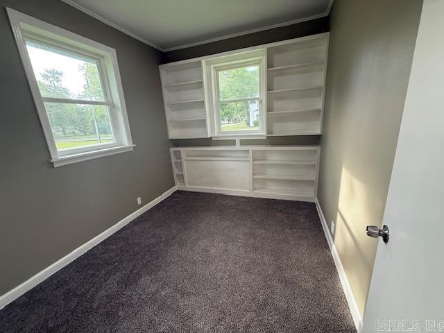 307 E 5th St, Carlisle, AR 72024 - unfurnished room featuring crown molding, healthy amount of natural light, dark carpet, and baseboards