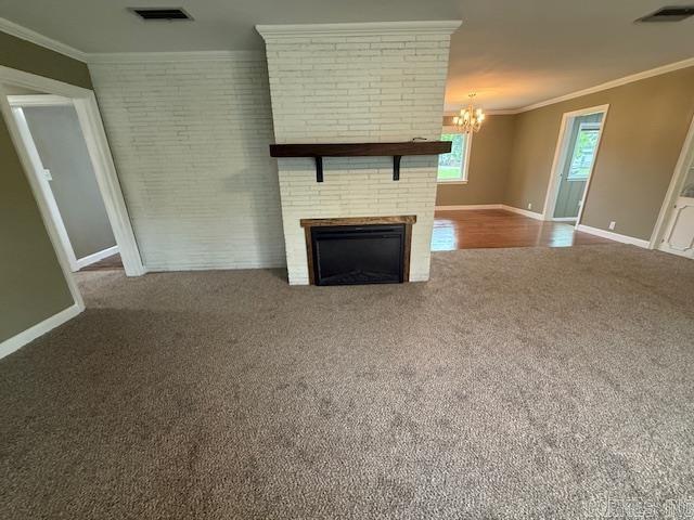 307 E 5th St, Carlisle, AR 72024 - unfurnished living room with carpet floors, a chandelier, ornamental molding, baseboards, and a brick fireplace