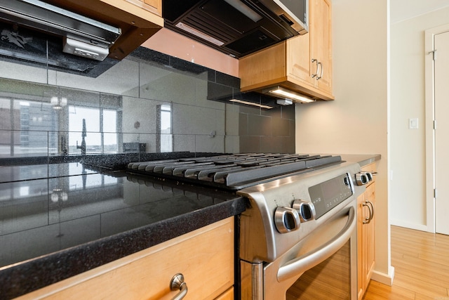 kitchen featuring stainless steel gas stove, light brown cabinets, exhaust hood, tasteful backsplash, and light wood finished floors
