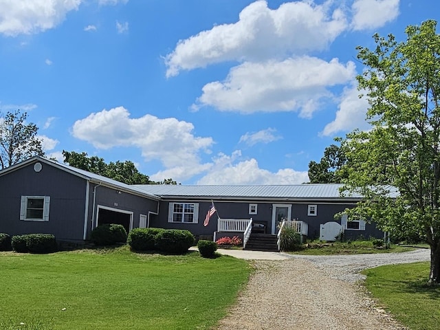 view of front of property with a front yard, a garage, metal roof, and driveway