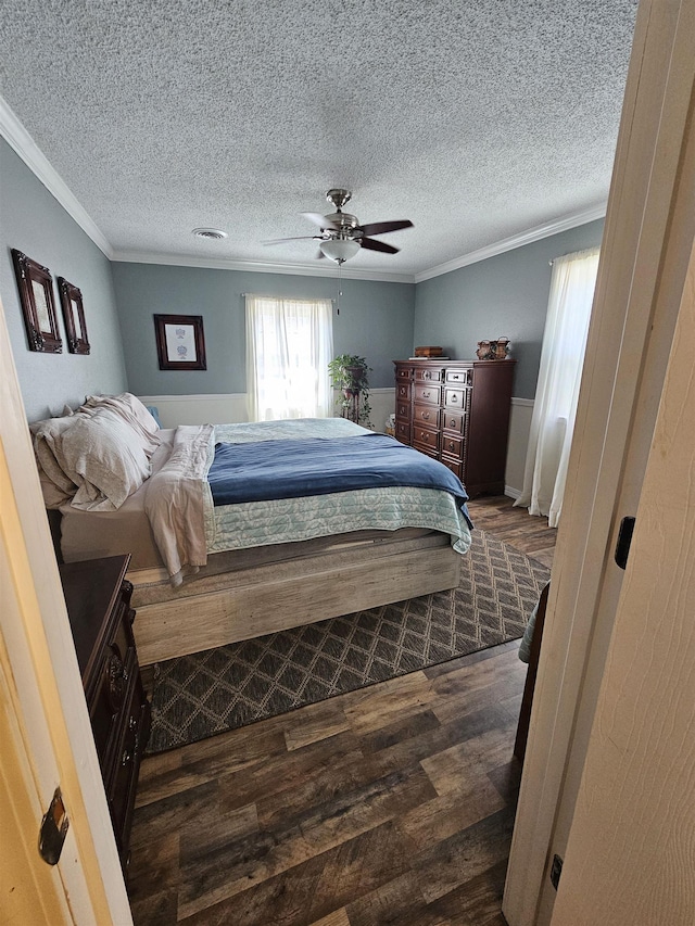 bedroom with dark wood-style floors, crown molding, a textured ceiling, and ceiling fan