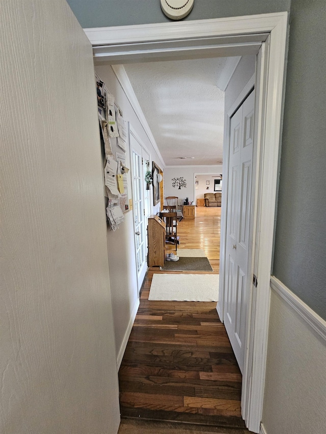 hallway featuring wood finished floors, french doors, and ornamental molding