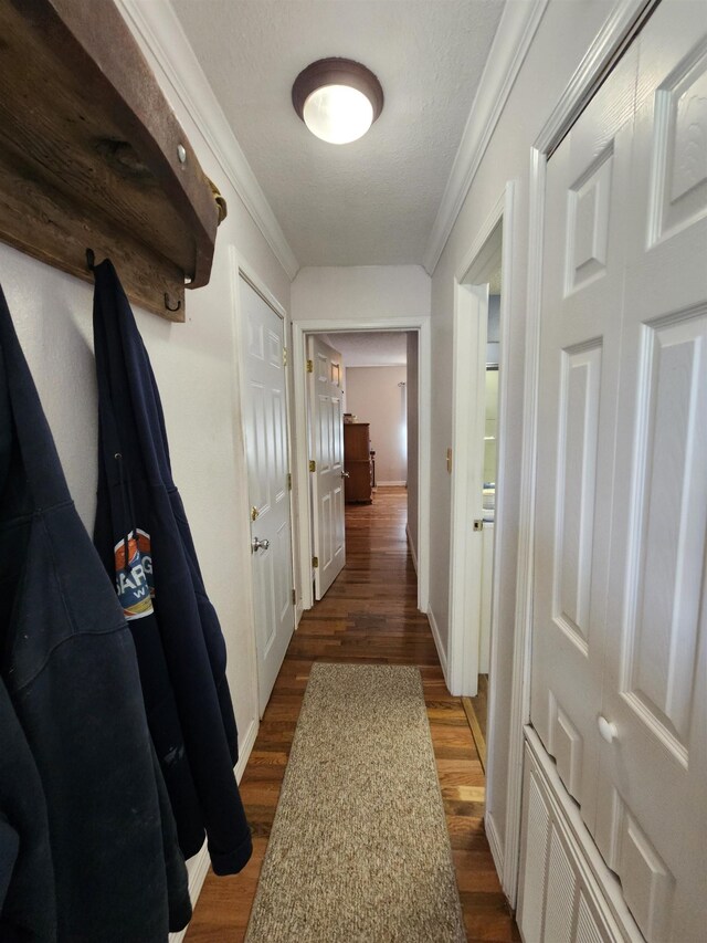 corridor with dark wood finished floors, ornamental molding, and baseboards