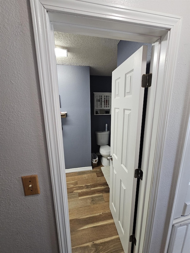 bathroom with wood finished floors, toilet, and baseboards
