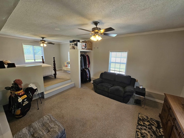 carpeted living room with ceiling fan, ornamental molding, plenty of natural light, a textured ceiling, and baseboards
