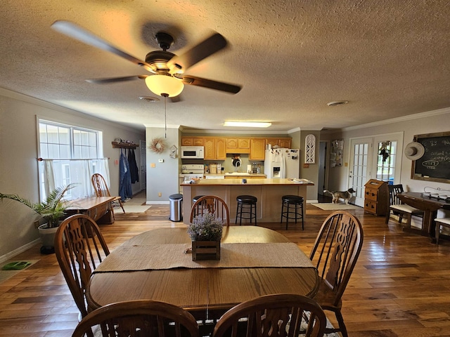 dining room with wood-type flooring, ornamental molding, a ceiling fan, a textured ceiling, and baseboards