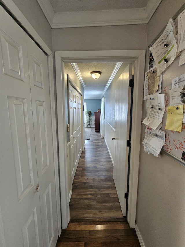 hall with ornamental molding, dark wood-type flooring, baseboards, and a textured ceiling
