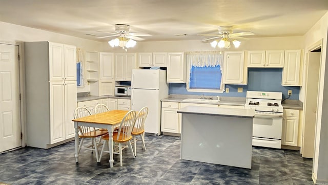 kitchen featuring white appliances, ceiling fan, a sink, and a center island