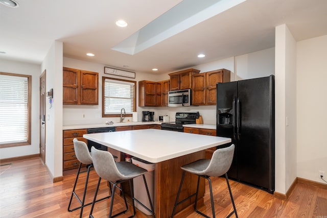 36 Lequita Pl, Hot Springs Village, AR 71909 - kitchen featuring black appliances, a sink, a breakfast bar area, light wood finished floors, and light countertops