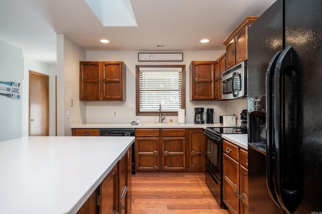 36 Lequita Pl, Hot Springs Village, AR 71909 - kitchen featuring black appliances, a sink, a skylight, light wood finished floors, and light countertops