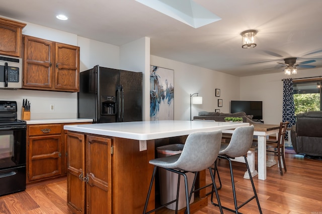 36 Lequita Pl, Hot Springs Village, AR 71909 - kitchen featuring black appliances, light wood-style floors, light countertops, a center island, and a kitchen breakfast bar