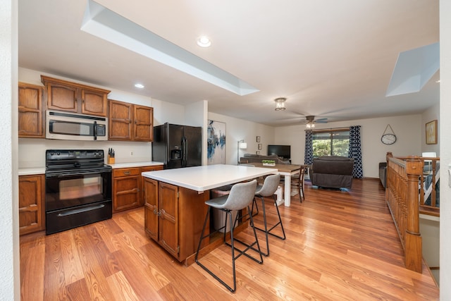 36 Lequita Pl, Hot Springs Village, AR 71909 - kitchen with black appliances, brown cabinets, light wood-type flooring, a kitchen bar, and recessed lighting