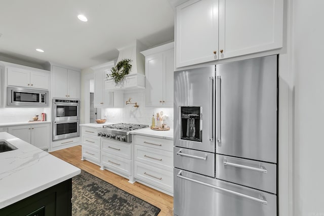 kitchen featuring stainless steel appliances, white cabinetry, backsplash, light wood-type flooring, and recessed lighting