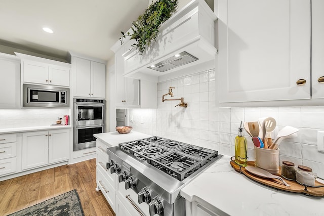 kitchen featuring appliances with stainless steel finishes, backsplash, and white cabinets