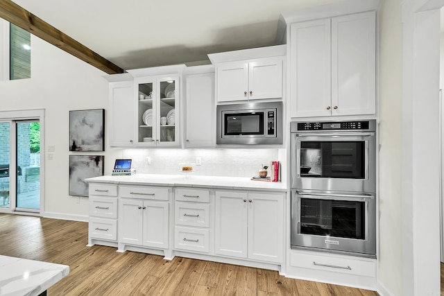 kitchen featuring stainless steel appliances, decorative backsplash, white cabinets, and light wood-style floors