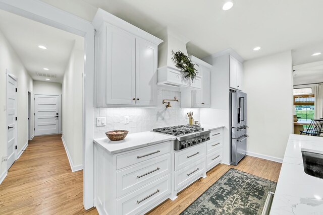 kitchen featuring stainless steel appliances, light wood-style floors, white cabinets, decorative backsplash, and recessed lighting