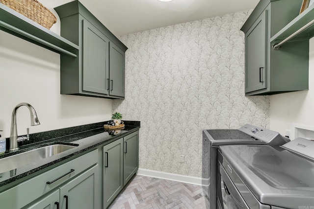 clothes washing area featuring washer and dryer, baseboards, wallpapered walls, and cabinet space