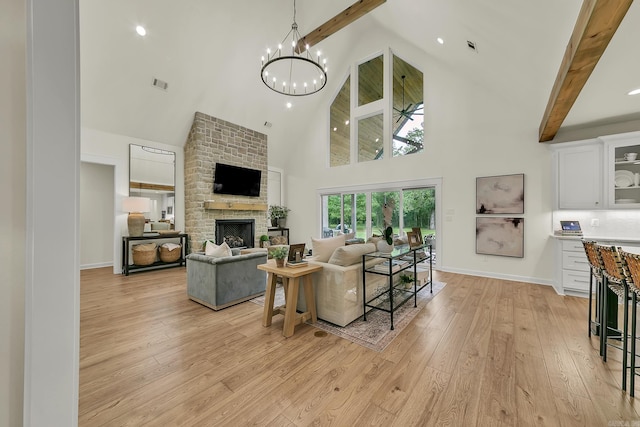 living room featuring high vaulted ceiling, beam ceiling, a fireplace, light wood-style floors, and a chandelier