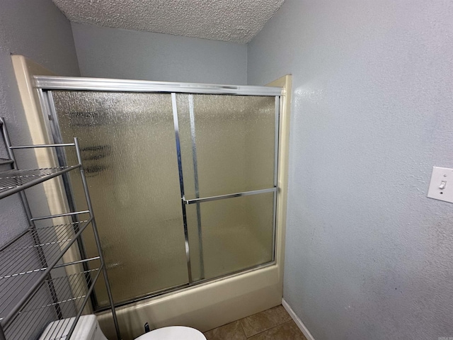 2608 Timbermist Cir, Benton, AR 72015 - bathroom featuring tile patterned flooring, a textured ceiling, enclosed tub / shower combo, baseboards, and toilet