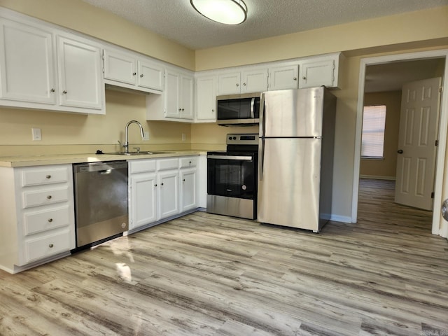 1807 Reservoir, Little Rock, AR 72227 - kitchen featuring stainless steel appliances, white cabinets, light wood-style floors, and a textured ceiling