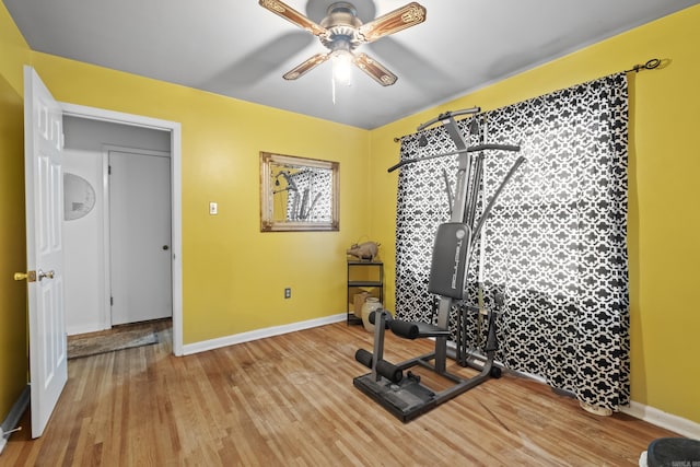 exercise room featuring baseboards, wood finished floors, and a ceiling fan
