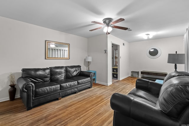 living area with a ceiling fan, wood finished floors, and baseboards