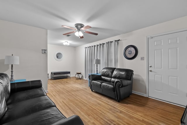living area featuring a ceiling fan, light wood finished floors, and baseboards