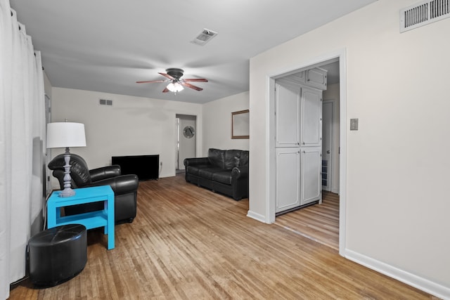 living area with light wood finished floors, ceiling fan, and baseboards