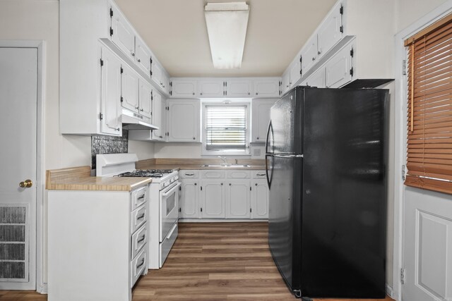 kitchen with freestanding refrigerator, gas range gas stove, and white cabinets