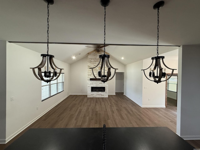 unfurnished dining area with a chandelier, wood finished floors, baseboards, and lofted ceiling