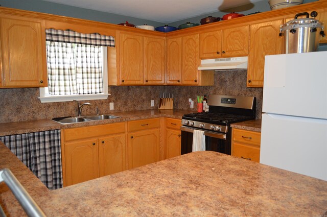 1059 Piney Rd, De Queen, AR 71832 - kitchen featuring gas range, freestanding refrigerator, under cabinet range hood, a sink, and decorative backsplash