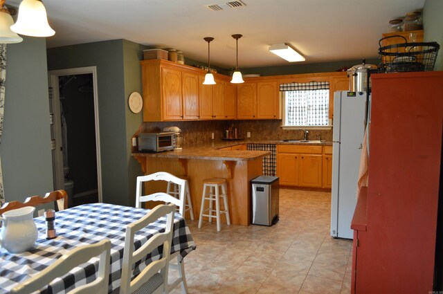 1059 Piney Rd, De Queen, AR 71832 - kitchen featuring freestanding refrigerator, a peninsula, tasteful backsplash, a sink, and hanging light fixtures