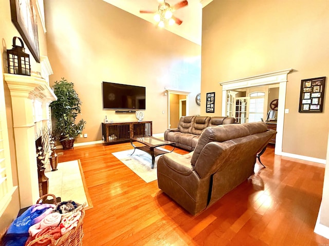 14 Windrush Pt, Little Rock, AR 72211 - living room featuring a towering ceiling, ceiling fan, a fireplace, baseboards, and light wood-style floors