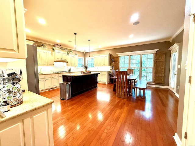 14 Windrush Pt, Little Rock, AR 72211 - kitchen with crown molding, hardwood / wood-style floors, a kitchen island, decorative backsplash, and cooktop