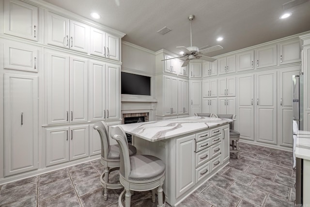 12 Darro Way, Hot Springs Village, AR 71909 - kitchen featuring a ceiling fan, a center island, white cabinets, a breakfast bar area, and crown molding