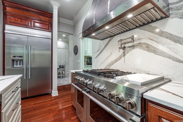12 Darro Way, Hot Springs Village, AR 71909 - kitchen with high end appliances, premium range hood, crown molding, dark wood-style floors, and ornate columns
