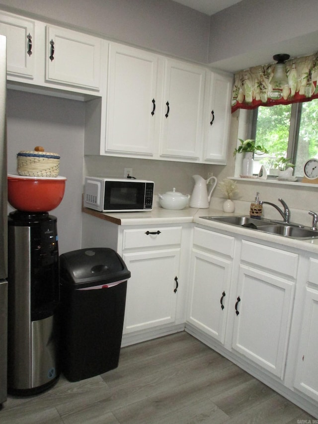 4005 Arapaho Trl, Little Rock, AR 72209 - kitchen with a sink, white cabinetry, light countertops, and light wood-type flooring