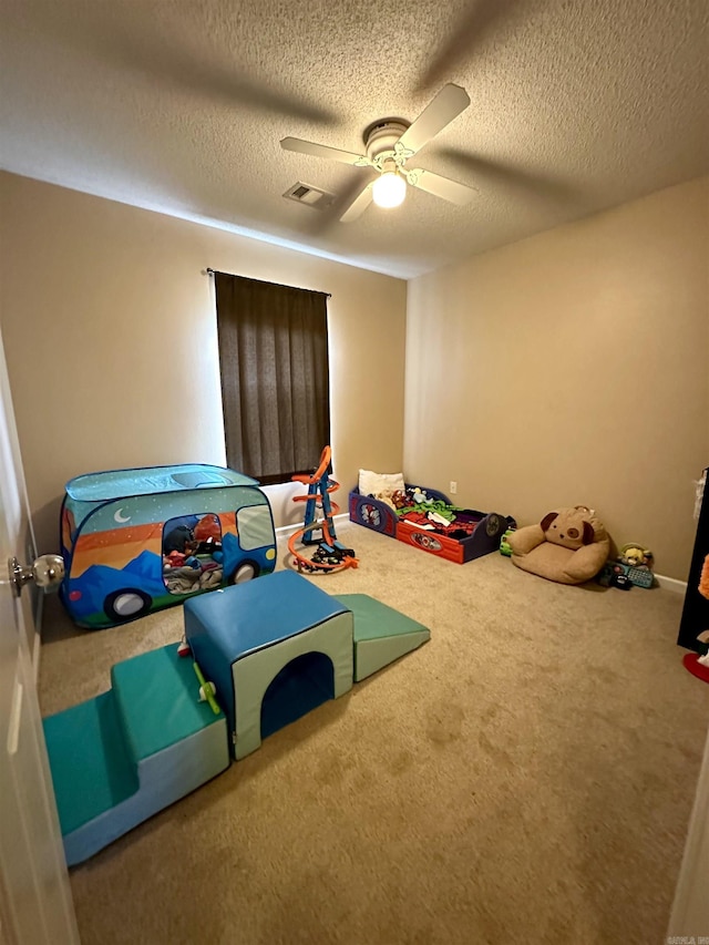 rec room featuring carpet, ceiling fan, and a textured ceiling