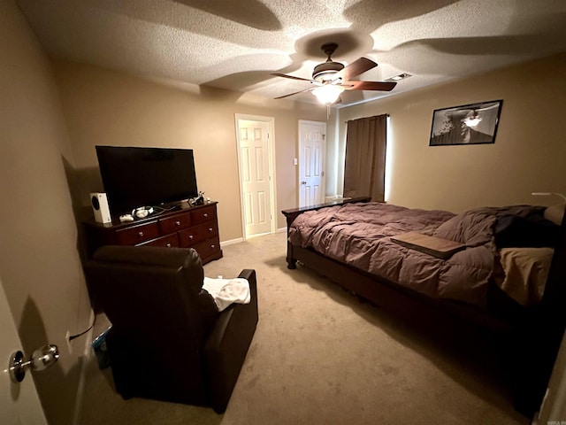 bedroom with a textured ceiling, light colored carpet, and a ceiling fan